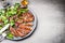 Sliced grilled beef steak with green leaves salad on rustic plate with cutlery.