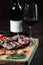 Sliced grilled T-bone steak tomatoes on a cutting board with bottle of wine and wineglass