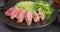 Sliced Grilled tuna steak with sliced avocado on a black stone serving board with teriyaki sauce