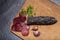 Sliced horse sausage, herbs and spices on cutting board