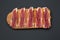 Sliced jamon Serrano or Iberico on cutting wooden board. Traditional spanish hamon on dark wooden background, top view.