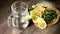 Sliced lemon cucumbers and mint leaves on a wooden cutting board next to a glass carafe with sparkling water