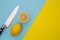 Sliced lemons and knife on minimal yellow and blue background