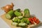 Sliced luffa or gambas or oyong fruit, an onion and some red chilies on a wooden cutting board