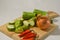 Sliced luffa or gambas or oyong fruit, an onion and some red chilies on a wooden cutting board