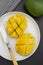 Sliced mango fruit on a white round plate ready to be served. Top view, healthy fruit breakfast or snack