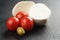 Sliced mozarella ball with tomato and olives on slate background