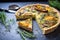 sliced mushroom quiche on a slate with herbs