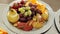 Sliced pear, orange, apple, strawberries and grapes lying on a large platter