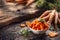 Sliced pieces of carrot in a bowl and a fresh bunch of carrots in the background