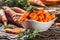 Sliced pieces of carrot in a bowl and a fresh bunch of carrots in the background