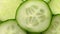 Sliced pieces of green cucumber stacked on a hill rotate, top view, spinning slowly in a circle, close up.