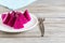 Sliced pink dragon fruit on white ceramic plate on vintage wooden table, selective focus