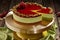 Sliced pistachio cheesecake with raspberry jelly on cake stand