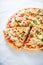 Sliced pizza with mozzarella cheese, chicken, sweet corn, sweet pepper and parsley on white background close up
