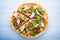 Sliced pizza with prosciutto (parma ham), arugula (salad rocket) and parmesan on blue wooden background