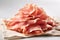 Sliced Prosciutto on Linen Cloth, light background, close-up. Prosciutto ham slices minimalistic image. Traditional italian