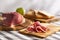 sliced prosciutto on a wooden board. pork ham on a light background. composition meat delicacy and bread.