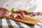 sliced prosciutto on a wooden board. pork ham on a light background. composition meat delicacy and bread.