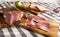 sliced prosciutto on a wooden board in sunny day. pork ham on a light background. composition meat delicacy and bread.