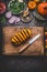 Sliced pumpkin on cutting board with knife and various vegetables and seasoning ingredients for tasty seasonal dish cooking, rusti