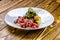 Sliced rare roast sirloin of beef with roasted vegetables on rustic wooden background