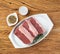 Sliced raw ancho beef, typical argentinian cut, over white plate with seasonings