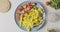 Sliced ripe red tomatoes and yellow paprika on a blue ceramic plate on a white table with organic natural ingredients