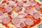 Sliced sausages on pizza close up.