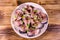 Sliced scomber fish with green onion on a ceramic plate on wooden table. Top view