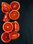 Sliced Sicilian red oranges on black stone background. Top view