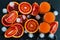 Sliced Sicilian red oranges and orange juice in small glasses on black stone background. Top view