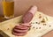 Sliced smoked sausage, salami on a cutting Board, spices, garlic, pepper, a glass of light beer