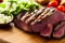 sliced stake on chopping board with herbs vegetables tomatoes