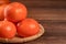 Sliced sweet persimmon kaki in a bamboo sieve basket on dark wooden table with red brick wall background, Chinese lunar new year