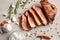 Sliced tasty steak with spices and salt on light background