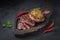 Sliced tenderloin steaks on wooden board, dark photo copy space