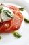 Sliced tomato, mozzarella, pesto and basil leaves on a gourmet platin