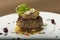 Sliced truffles topped on a grilled steak,  beef and pork,  with vegetable and sauce,  on a white plate,  brown background