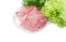 Sliced uncooked pork on dish on background of parsley and lettuce