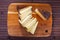 Sliced wedge of aged sheep cheese on wooden board