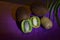 Sliced and whole kiwi, coconuts on a polished purple table