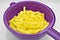 Sliced â€‹â€‹potatoes in purple plastic colander