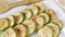 Slices of baked zucchini watered with oil with provencal herbs. Healthy food, cooking vegetables with spices. Close-up, glass dish