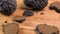 Slices of a black truffle mushroom are falling on the wooden board