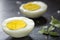 Slices of boiled hard eggs on a dark slate with green oregano