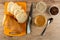 Slices of bread on cutting board, knife, bowls with sunflower seeds, raisin, jar with peanut butter, spoon on table. Top view