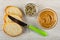 Slices of bread, knife, bowl with mix of sesame, sunflower seeds, pumpkin seeds, bowl with peanut butter on table. Top view