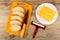 Slices of bread, knife on cutting board, piece of marble cheese in plate, cheese cutter on table. Top view