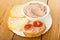 Slices of bread, liver pate in bowl, sandwich with liver paste and tomato in plate on table